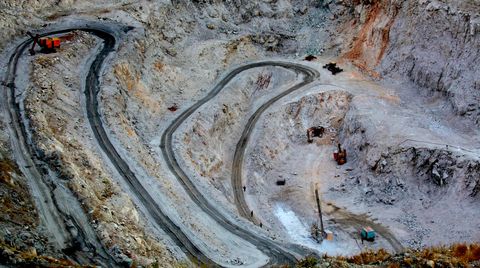 A large open pit mine with several excavators standing around.