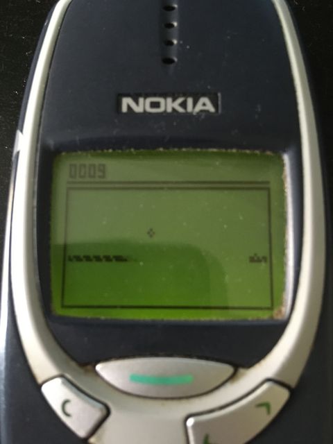 A Nokia 3310 phone with the game Snakes on the screen.